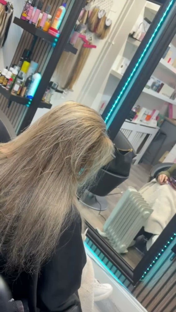 A client having long hair sectioned and dried at the styling chair